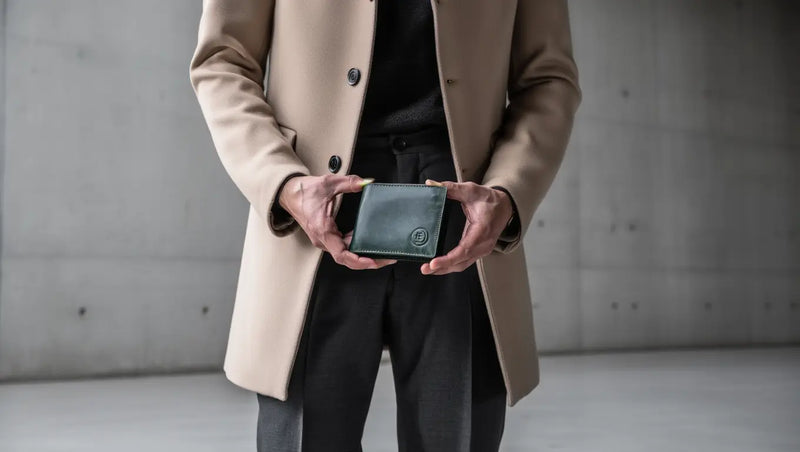 man holding a green genuine leather wallet in a modern outdoor setting